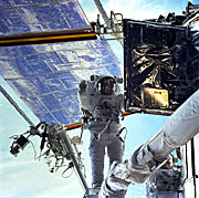 John Grunsfeld is preparing to insert the new radio transmitter in one of Hubble's bays.